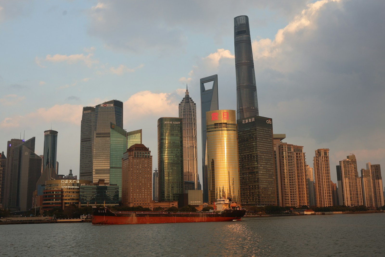 Modern skyscrapers and a cargo ship on the water.