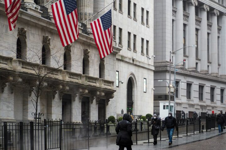 a group of people walking down a street next to tall buildings