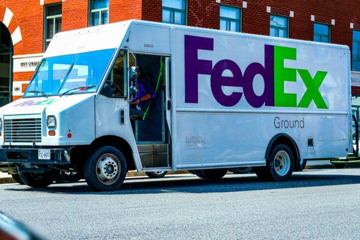 man in green jacket standing beside white and blue van during daytime