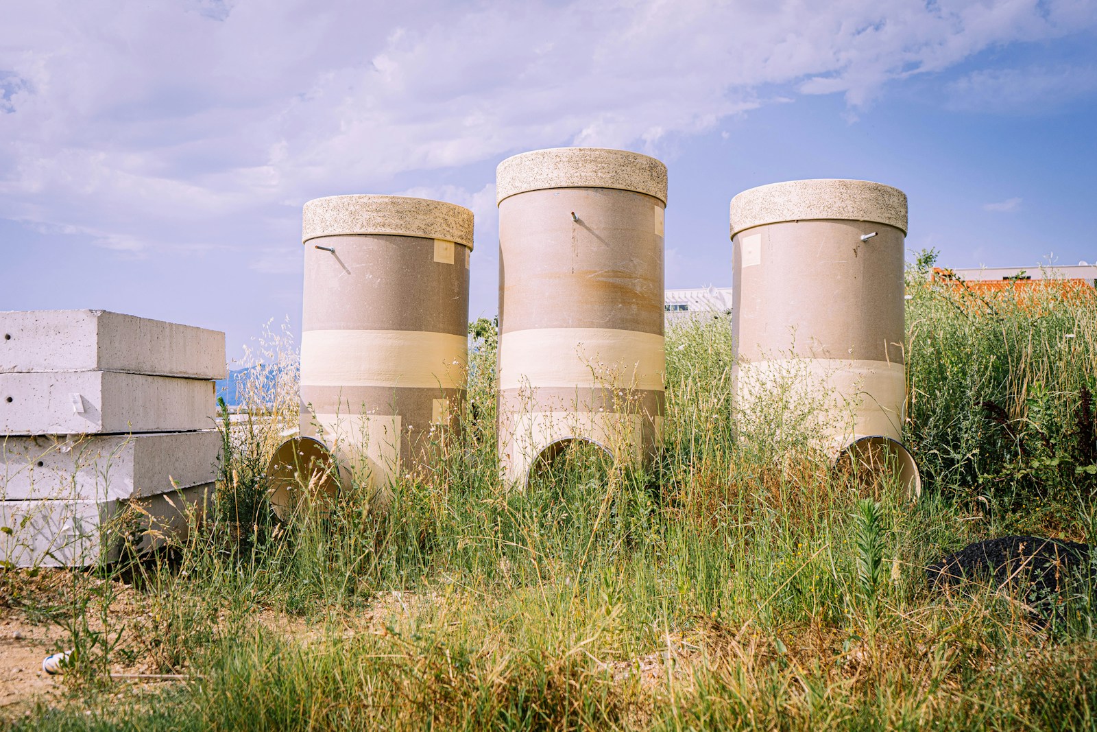 white and brown concrete barrels on green grass field under white clouds and blue sky during